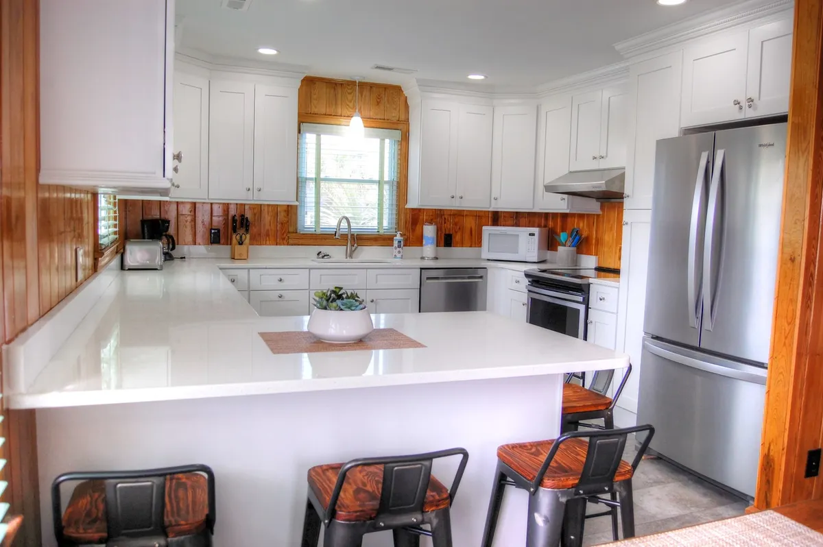 A beautifully lit kitchen with a central island, stainless steel appliances, and a window that lets in ample natural light. The island is prepped for baking or casual dining, and the surrounding counters and cabinetry highlight the kitchen's modern and functional design.